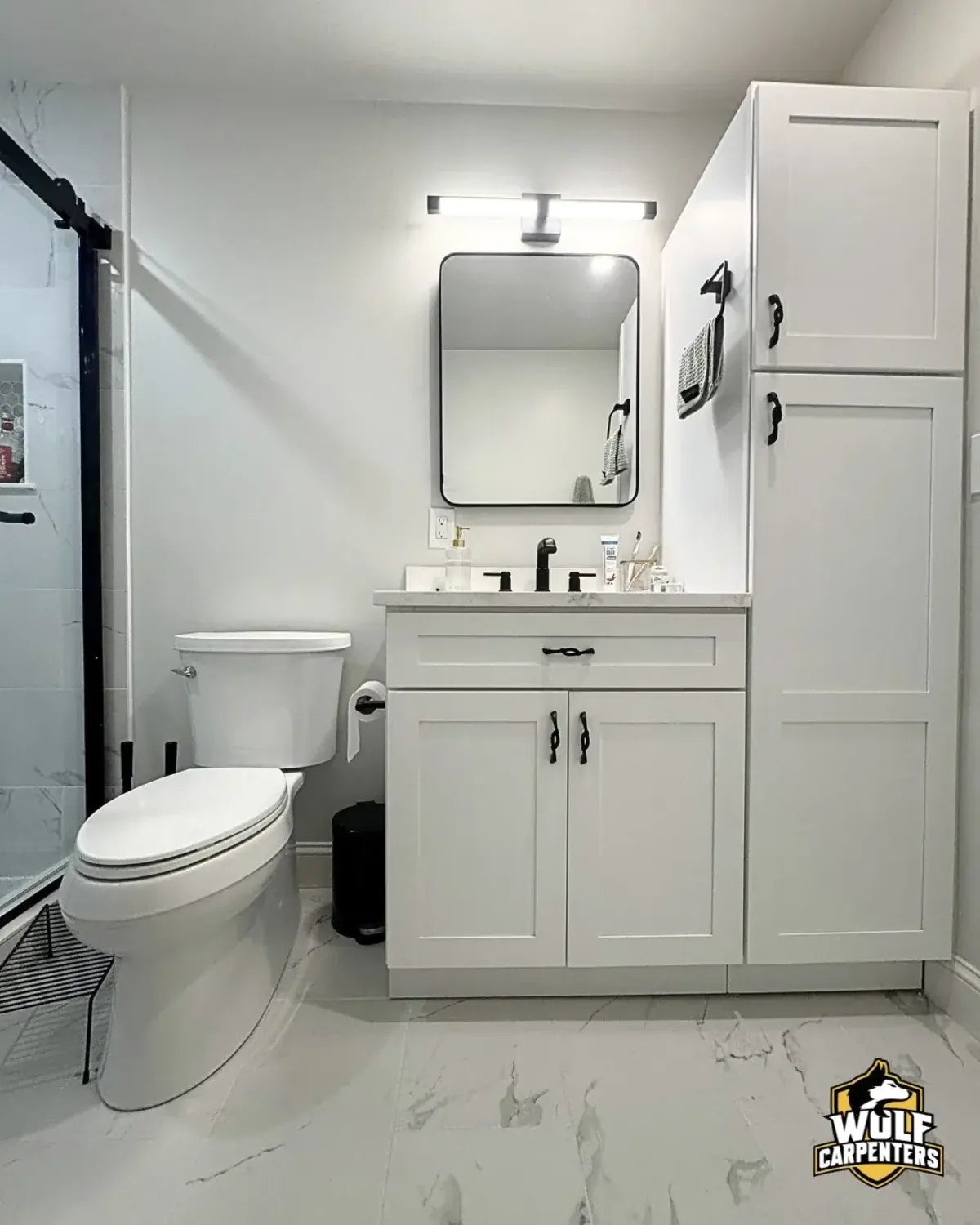 White marble-look bathroom renovation in Peabody, MA with a glass shower and shaker vanity