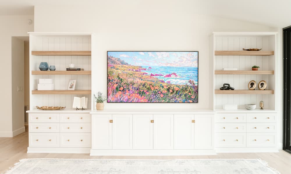 “White custom built-in cabinets with open wood shelves and center TV wall unit in a modern living room.”